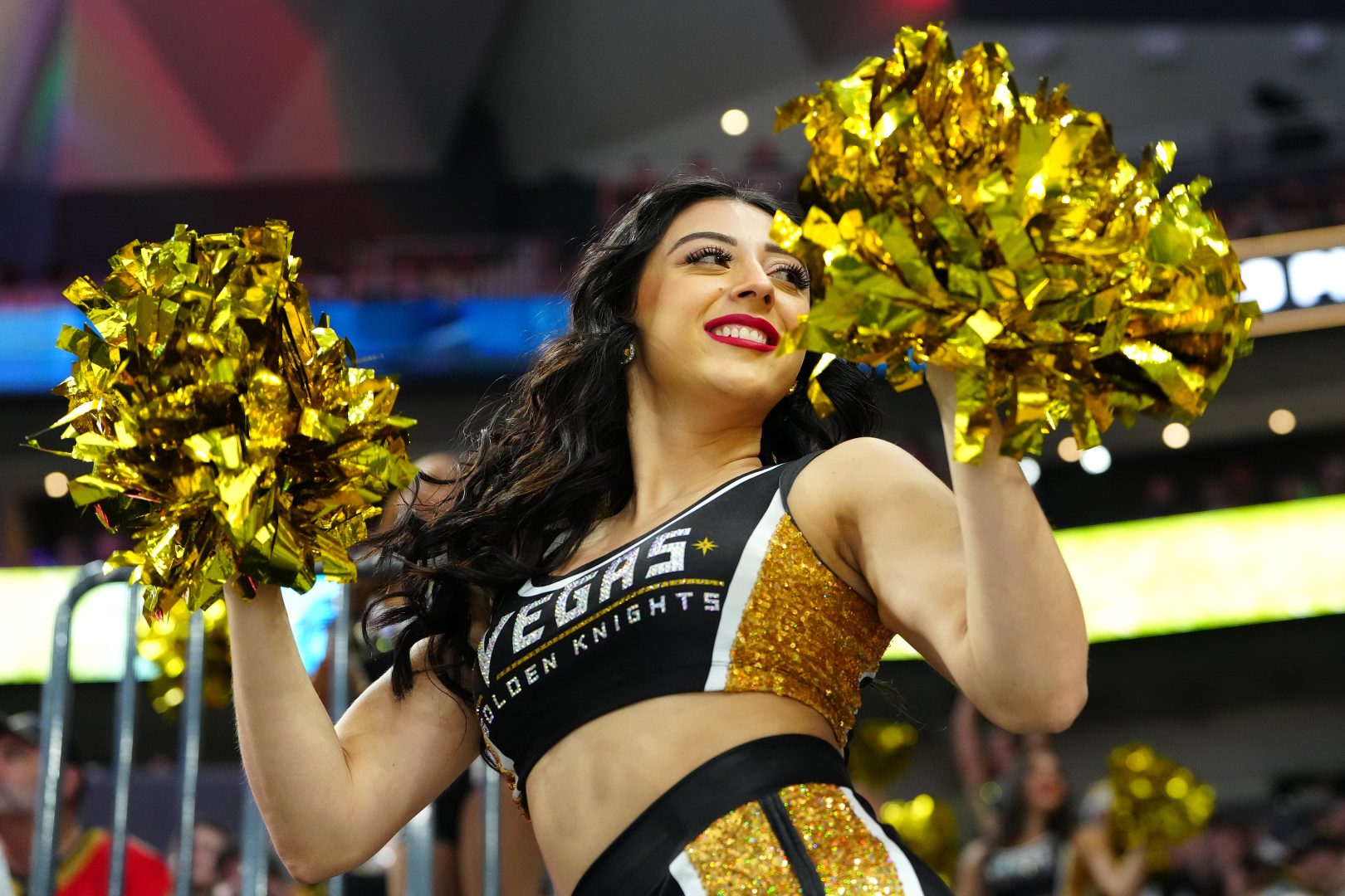 Vegas Golden Knights cheerleader performs with gold pom-poms during a game at T-Mobile Arena