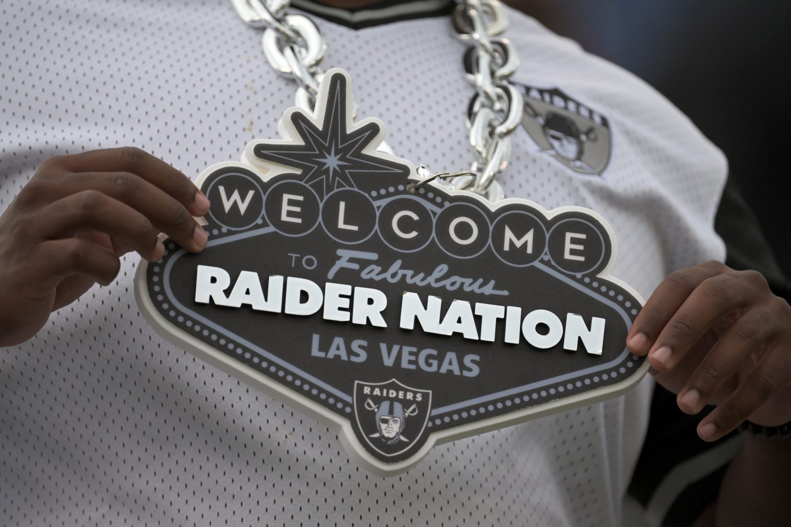 A Las Vegas Raiders fan holds a “Raider Nation” necklace.