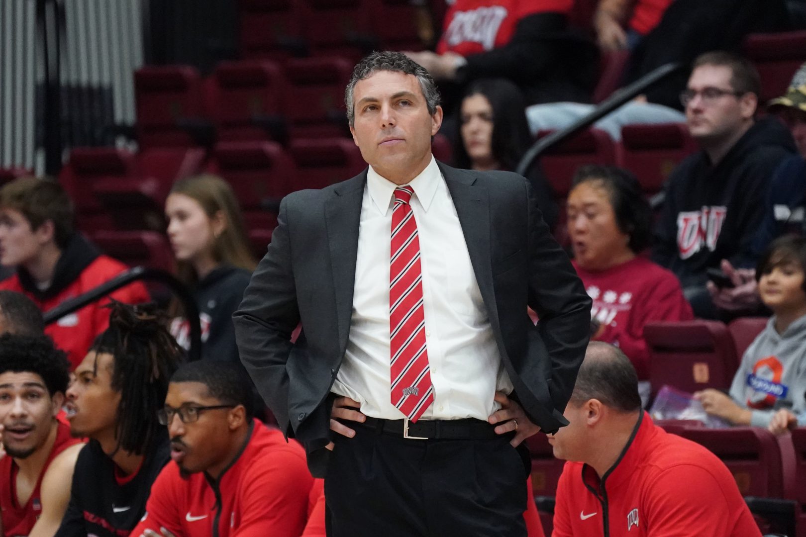 UNLV coach Josh Pastner stands with his hands on his hips on the sideline during a game.