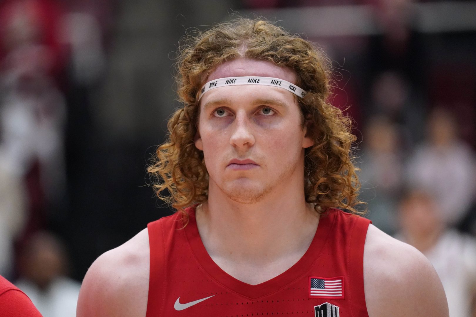 UNLV forward Walter Brown stands on the court during the national anthem wearing a red jersey and white headband.