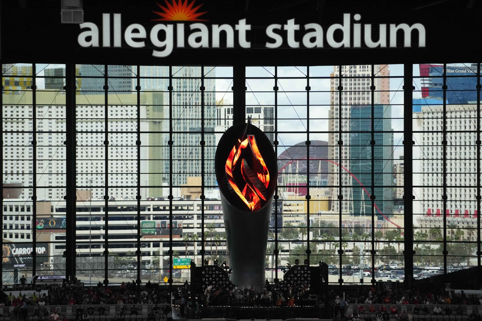 The Al Davis memorial torch glows inside Allegiant Stadium with the Las Vegas Strip visible through the giant north end windows.