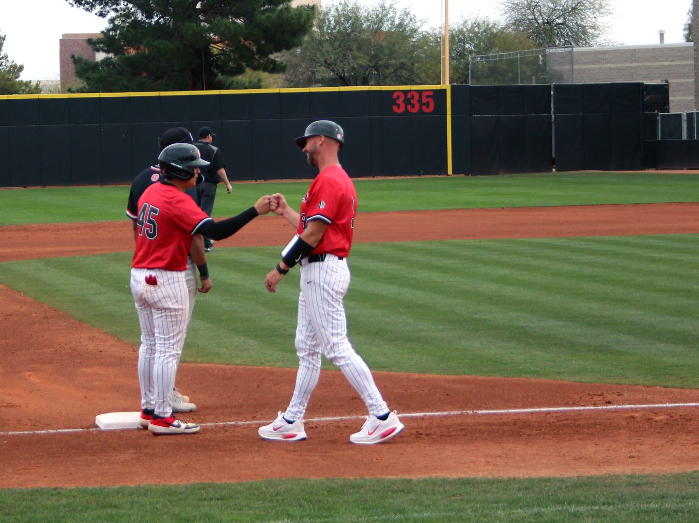 UNLV outfielder Rylan Morris gets a fist bump from head coach Cory Vanderhook at first base.