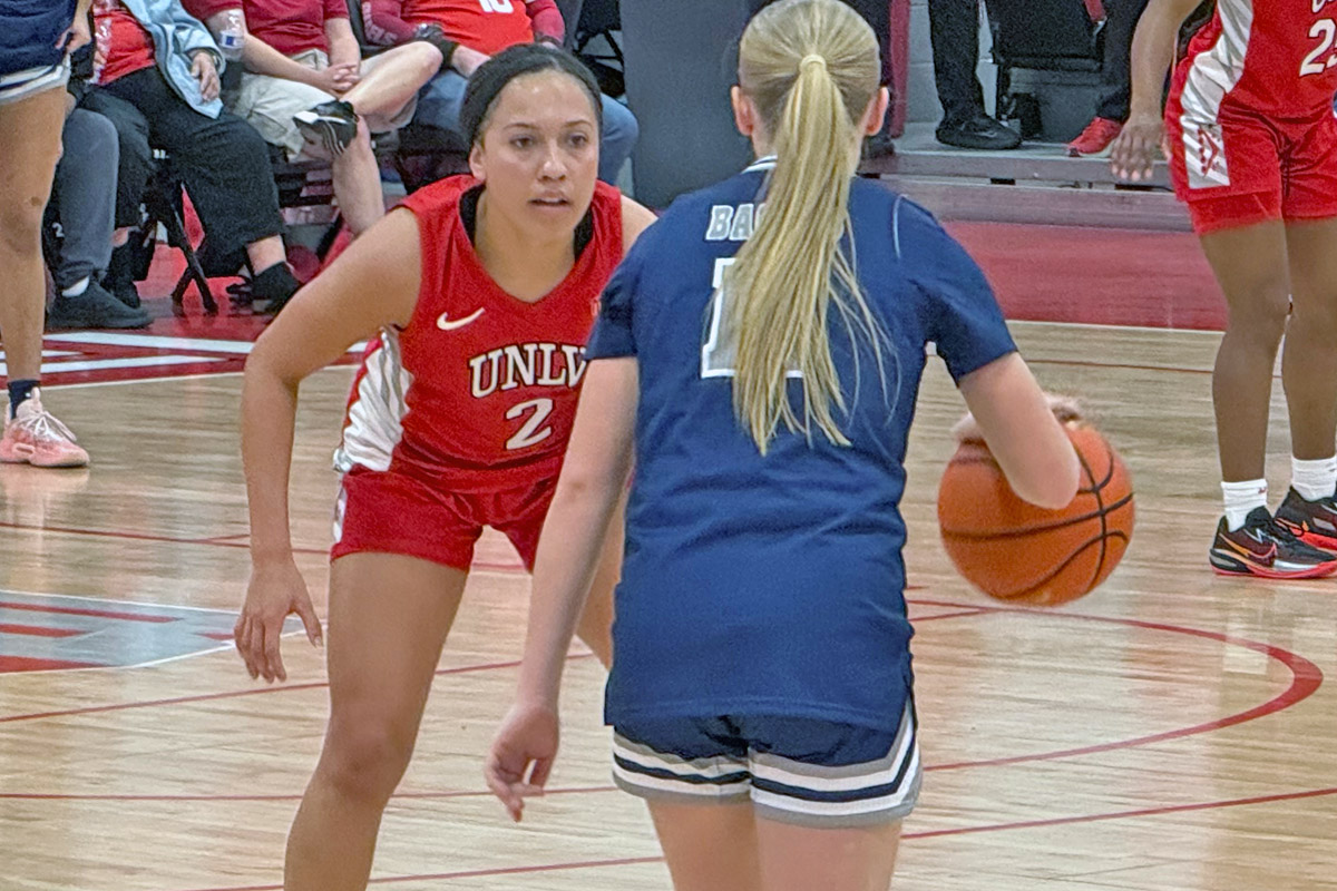 UNLV guard Mariah Elohim crouches in a defensive stance in front of a Nevada ballhandler.