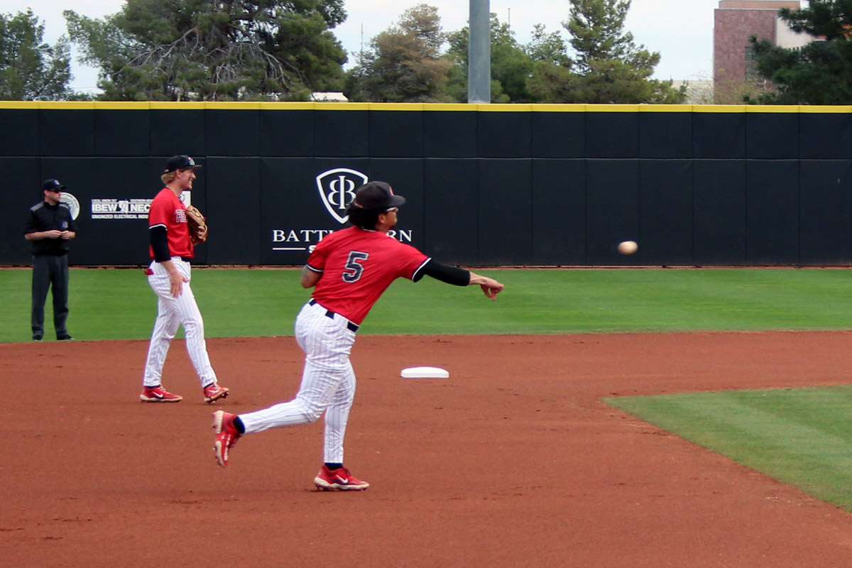 UNLV infielder Drew Barragan (#5) throws across the infield during an early-season game, with a teammate set behind him on the dirt.
