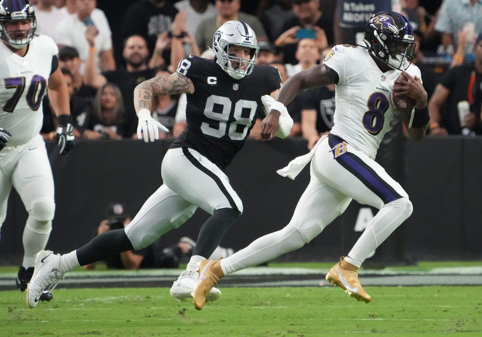 Baltimore Ravens quarterback Lamar Jackson (8) runs as Las Vegas Raiders defensive end Maxx Crosby (98) closes in at Allegiant Stadium.