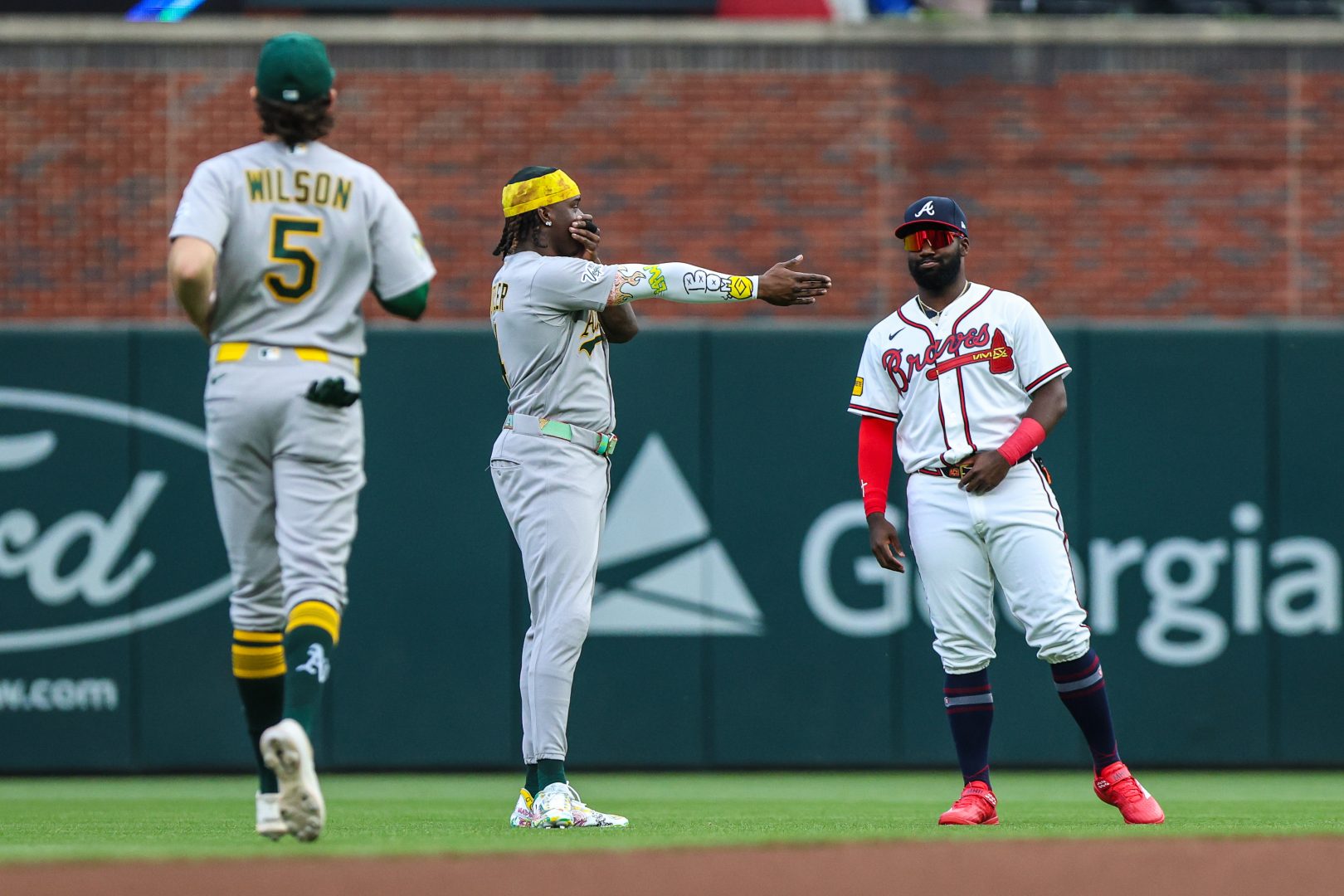 Lawrence Butler and Jacob Wilson talk with Michael Harris II before the Athletics face the Braves in Atlanta