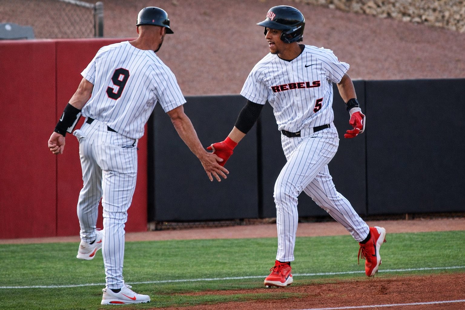UNLV baseball player Drew Barragan high-fives Associate Coach Cory Vanderhook after scoring at Earl E. Wilson Stadium.