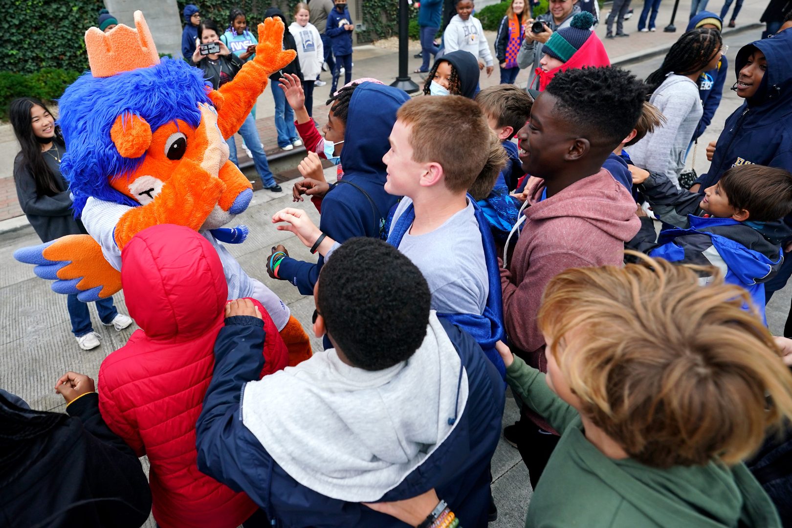 Children greet Gary the Lion, FC Cincinnati’s mascot, during a downtown Cincinnati street festival tied to the city’s 2026 World Cup hosting bid.