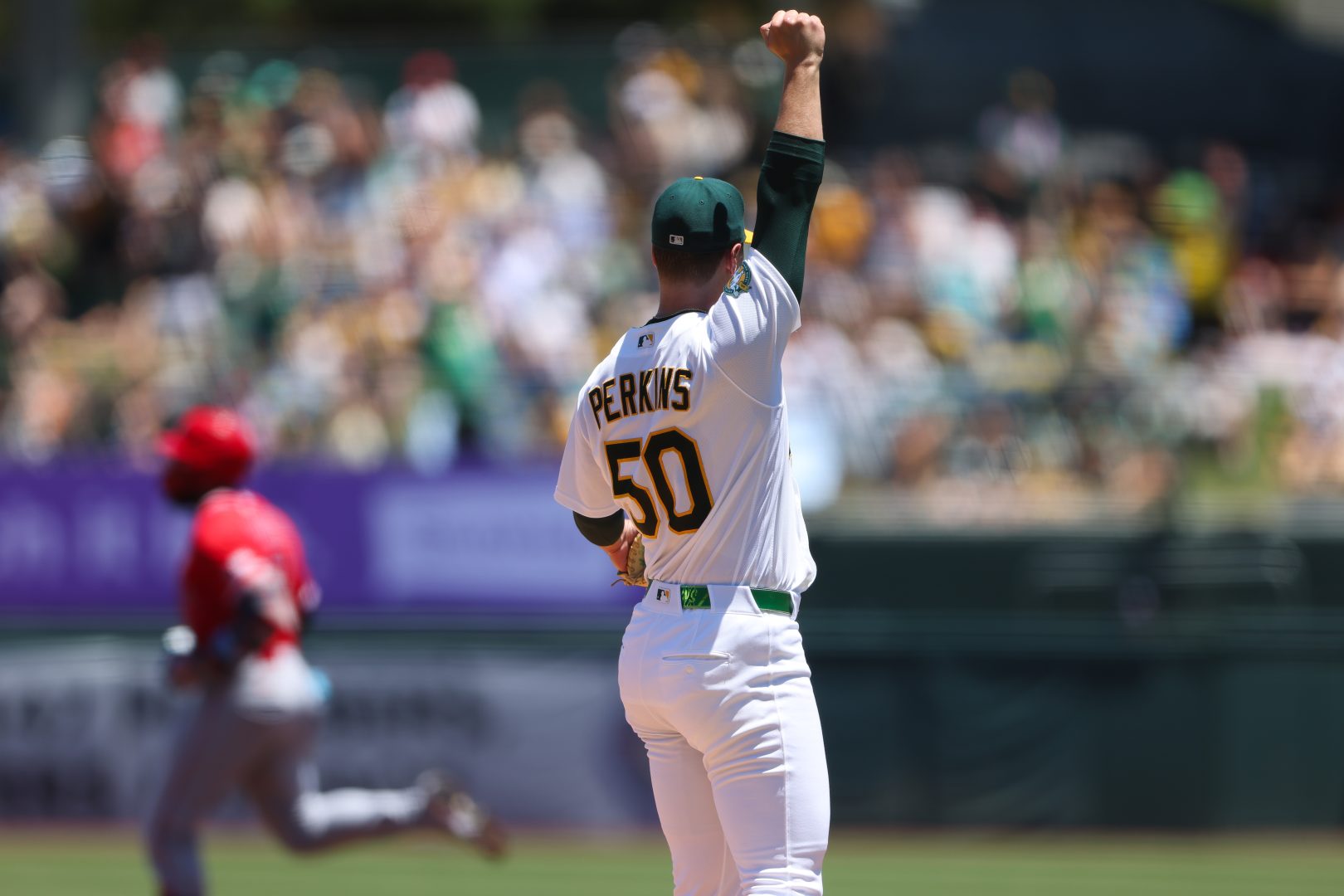 Athletics pitcher Jack Perkins reacts after right fielder Colby Thomas makes a leaping catch against the Los Angeles Angels.
