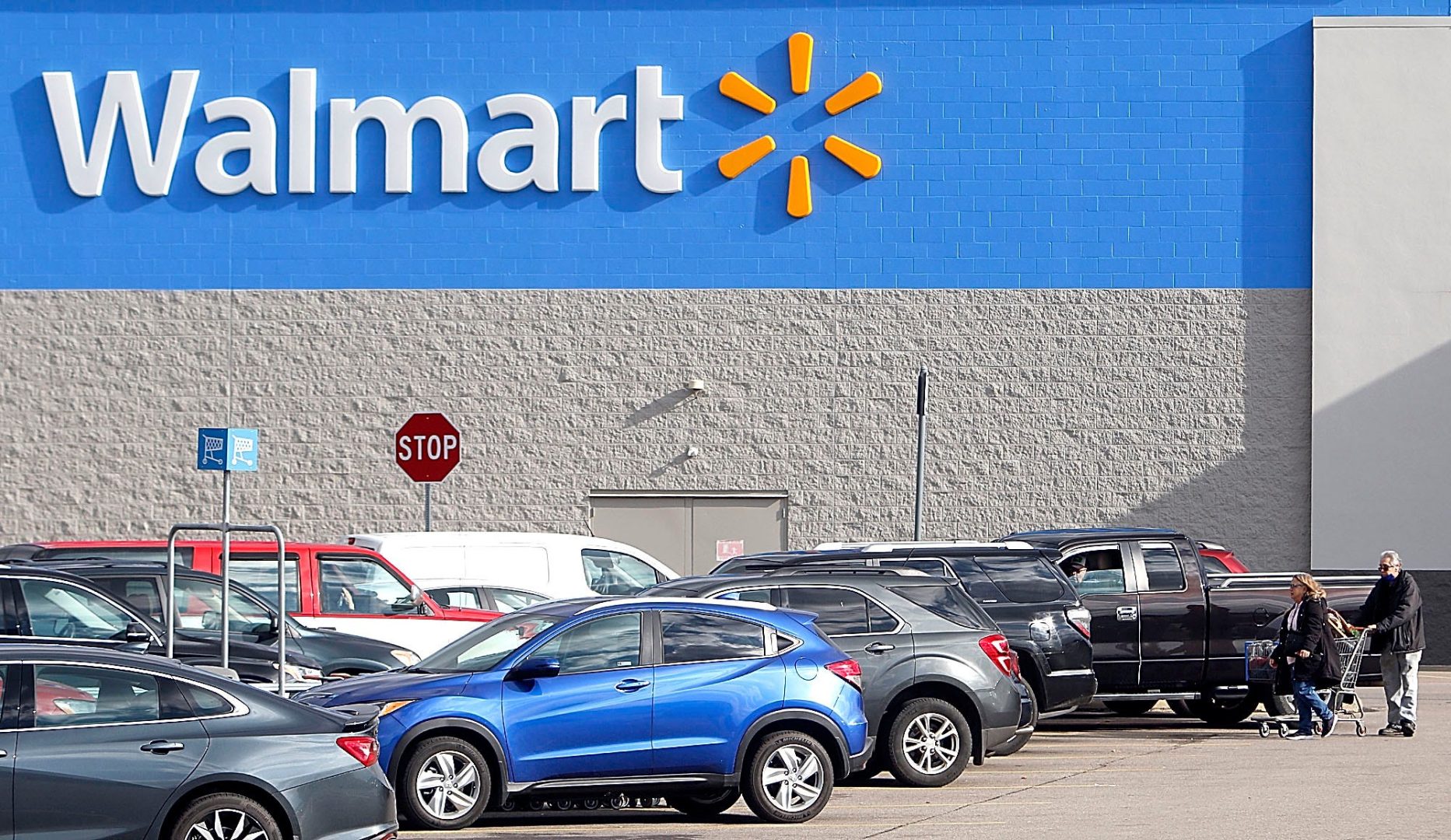 Walmart shoppers return to their cars after making their purchases