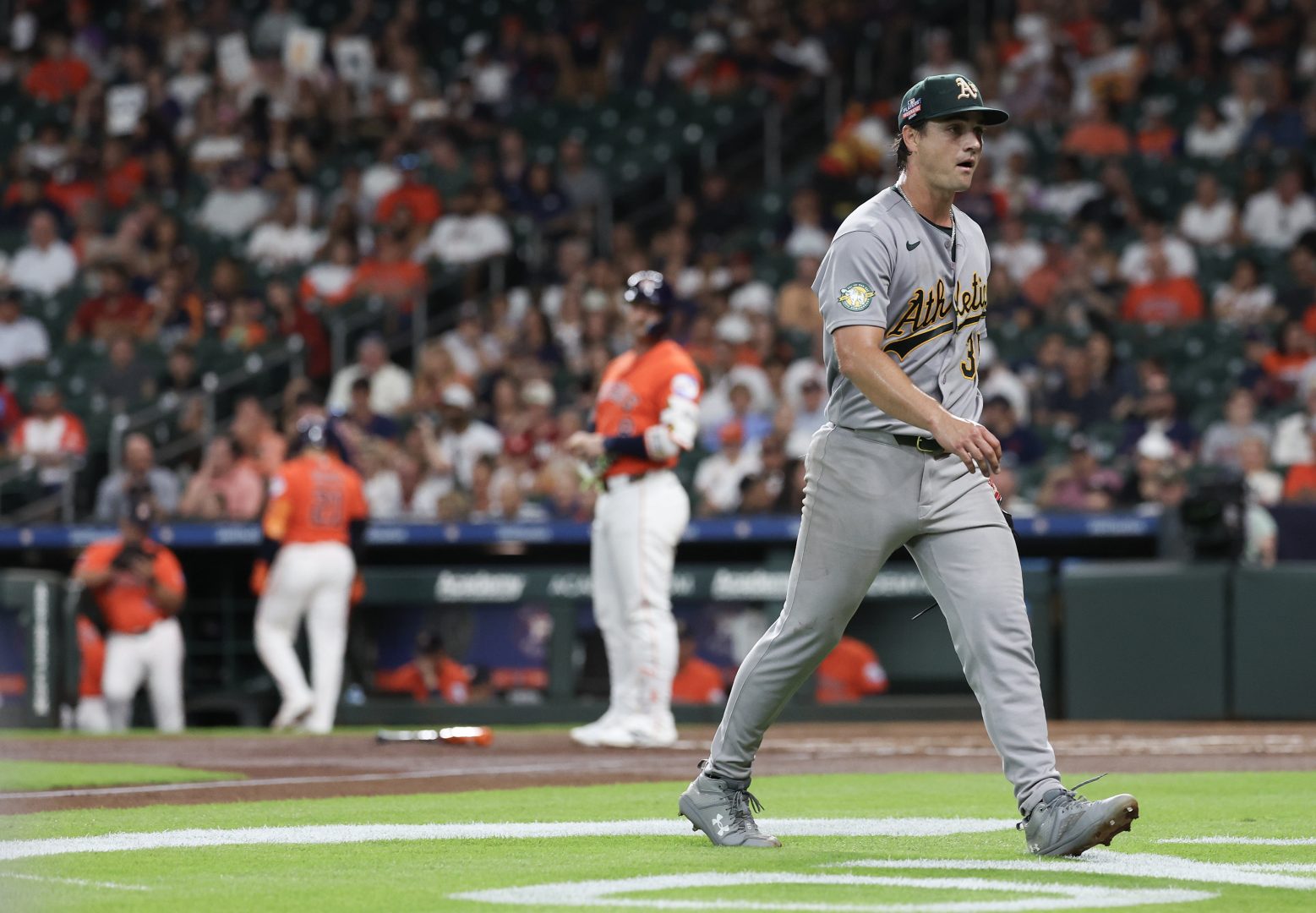 Athletics starting pitcher J.T. Ginn walks back to the dugout after striking out Christian Walker