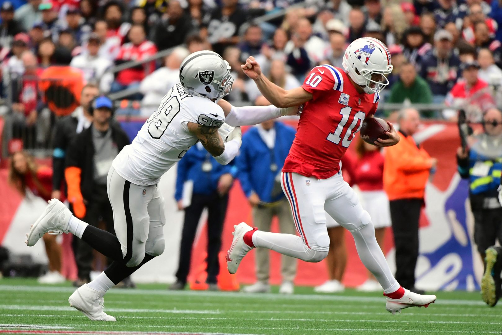 New England Patriots quarterback Drake Maye runs against Las Vegas Raiders defensive end Maxx Crosby at Gillette Stadium.